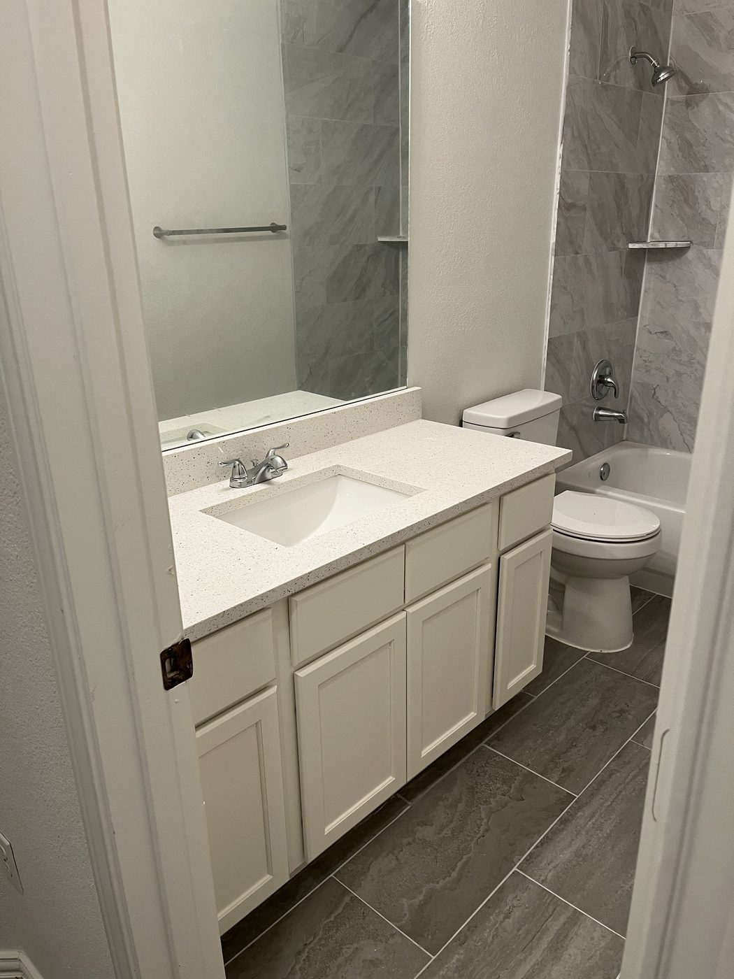 Bathroom vanity and tub with marble tile surround