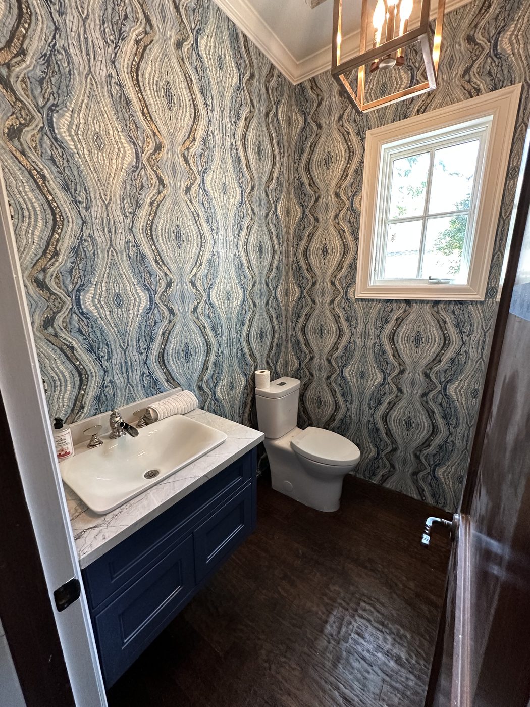 Powder room with patterned wallpaper and navy vanity